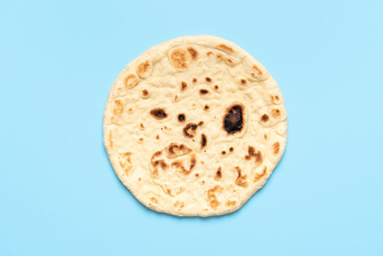 Naan bread isolated on a blue background. Indian flatbread above view