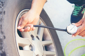 asian man pumping air to his car tyre checking air pressure and filling air in the tires of his car