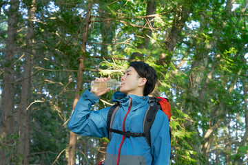 ペットボトルの水を飲む登山中の男性