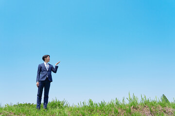 手のひらで青空を指すビジネスマン コピースペースあり