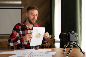 Male in shirt show stats graph pad making promo videoblog or photo session in camcorder to tripod. Vlogger selfie sale solution or finance advisor management information, marketing lecture © Andrii Lysenko