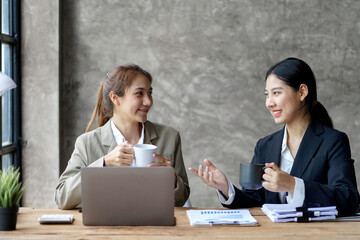 Two young beautiful Asian business woman in the conversation, exchanging ideas at work.