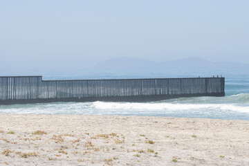 Fototapeta na wymiar The border fence between the U.S. and Mexico viewed from the beach at the Border Field State Park in San Diego, California. It separates San Diego from Tijuana and extends into the Pacific Ocean.