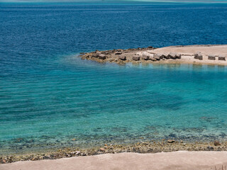 Beautiful landscape of the stone coast of the blue sea against the blue sky.