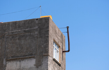 An unpainted old building plastered with cement. tin pipe chimney.