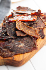 Beef jerky meat. Dried sliced meat on wooden cutting board.