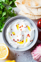 Whipped feta cheese dip with garlic and lemon in gray bowl. Greek cuisine concept.