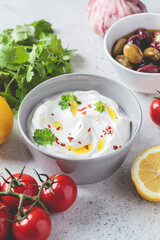 Whipped feta cheese dip with garlic and lemon in gray bowl. Greek cuisine concept.