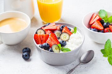 Cottage cheese with strawberries, nuts and blueberries in gray bowl for breakfast. Summer recipe.