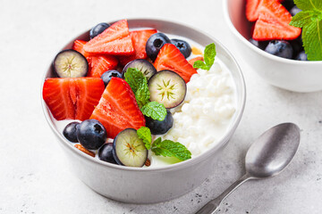 Cottage cheese with strawberries, nuts and blueberries in gray bowl for breakfast. Summer recipe.