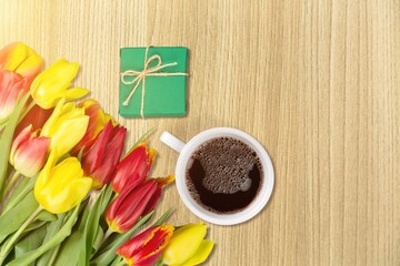 Beautiful fresh tulips with a cup of coffee and gifts box.
