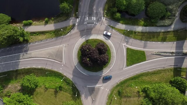 Aerial footage of a traffic roundabout, roads, lanes with driving cars. Drone movie taken from above in Sweden in summer. Transportation concept.