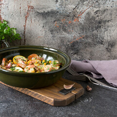 ceramic baking sheet with baked chickpeas with shrimp with lemon and garlic on a dark table