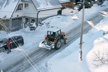 tractor removing snow in mountain suburban area. bulldozer is de-icing roads in countryside