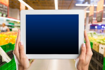 Retail management. Worker hands holding tablet on blurred supermarket background