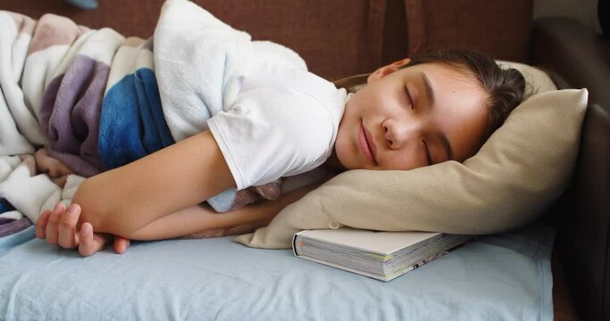 A girl is sleeping with a book under her pillow. 4k video.