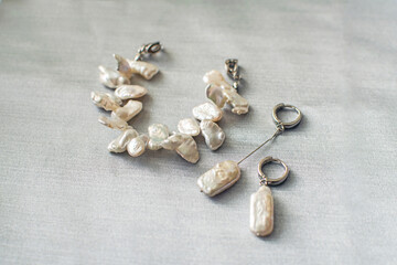 Fototapeta na wymiar Luxury baroque pearl earrings and bracelet on a silver background.