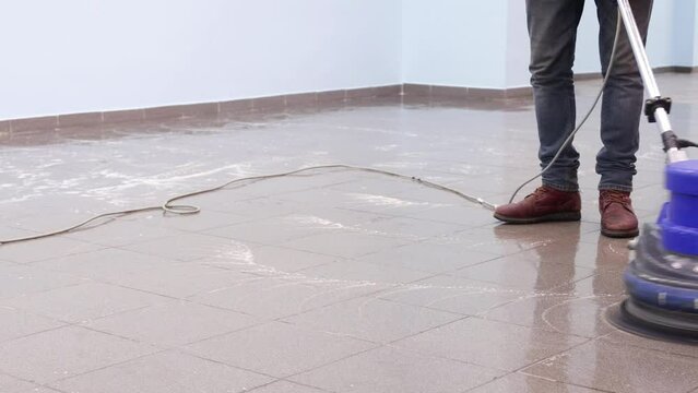 the cleaner washes a pier with a professional polisher machine. Cleaning floor in office building lobby
