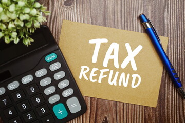 Tax Refund typography text on paper card with calculator on wooden background