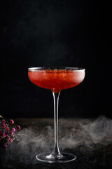 Strawberry margarita cocktail in a beautiful glass with crushed ice and smoke on a dark background. Tropical alcoholic drink with tequila