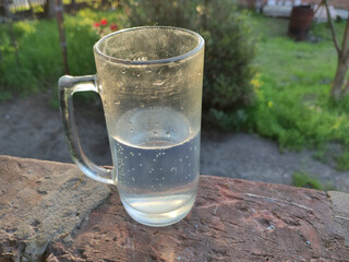 Half empty glass stands on brick background
