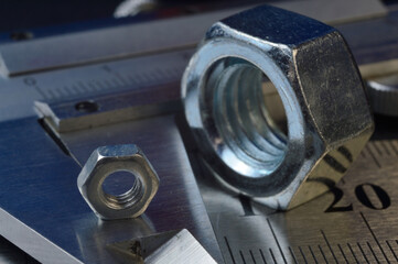 Accurate measuring tool caliper and metal ruler lie in place with nuts. close-up.
