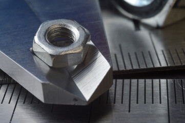 Accurate measuring tool caliper and metal ruler lie in place with nuts. close-up.