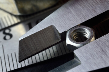 Accurate measuring tool caliper and metal ruler lie in place with nuts. close-up.