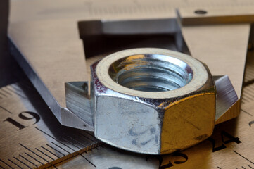 Accurate measuring tool caliper and metal ruler lie in place with nuts. close-up.