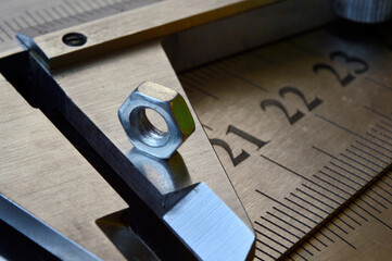 Accurate measuring tool caliper and metal ruler lie in place with nuts. close-up.