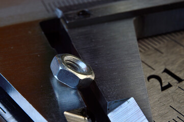 Accurate measuring tool caliper and metal ruler lie in place with nuts. close-up.