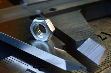 Accurate measuring tool caliper and metal ruler lie in place with nuts. close-up.