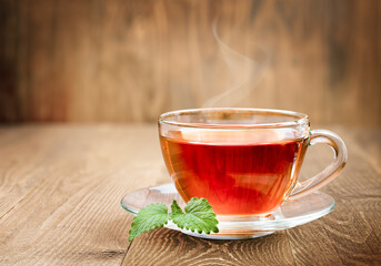 transparent glass cup of hot tea and Melissa leaves on wooden background