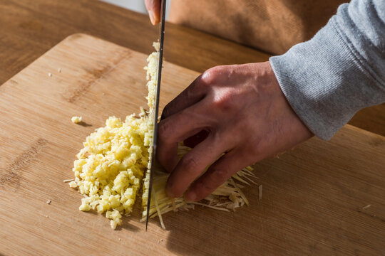 Chef hand at the end of the chopper on the cutting board cut ginger only hands no face