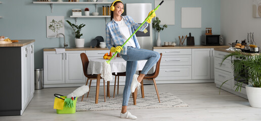 Young woman having fun while cleaning kitchen