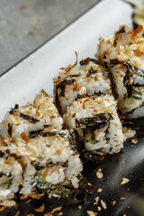 Golden dragon sushi roll with tuna, eel, cucumber, sesame seeds and tobiko caviar on wood background