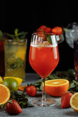 Colorful refreshing drinks for summer, cold strawberry lemonade juice with ice cubes in the glasses garnished with sliced fresh lemons