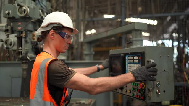 Industrial worker operating cnc turning machine in metal machining industry