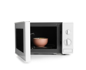 Bowl with tasty corn flakes in microwave oven on white background
