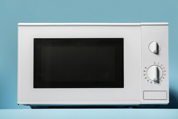 Fototapeta premium New modern microwave oven on blue background