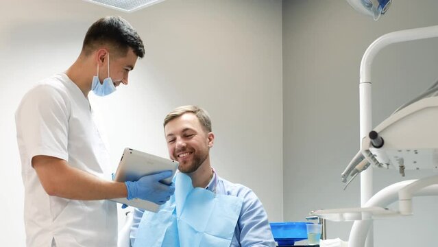 The dentist uses a tablet to show the patient images of the teeth. Painless dental treatment