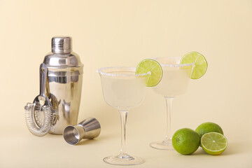 Glasses of tasty margarita cocktail with shaker on color background