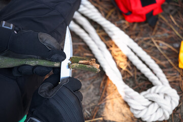 Male tourist making wooden stake in forest, closeup