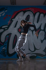 Silhouette of young woman hiphop dancer (breakdancer)dancing on graffiti studio background....