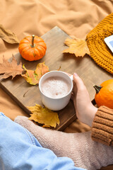 Woman drinking tasty pumpkin coffee on bed