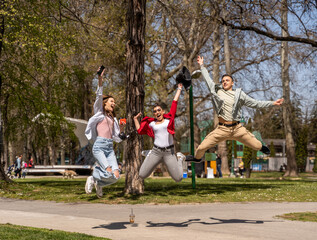 Obraz premium Friendship, freedom, happiness and people concept - group of happy friends dancing and jumping in park
