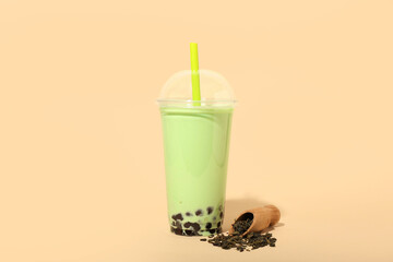 Plastic cup of tasty bubble tea on beige background