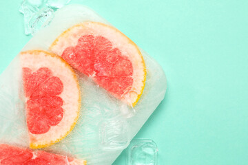 Fresh grapefruit slices frozen in ice on turquoise background