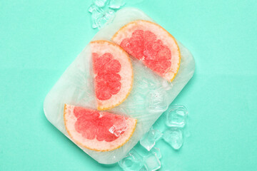 Fresh grapefruit slices frozen in ice on turquoise background