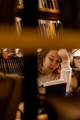 Girl reading between bookshelves